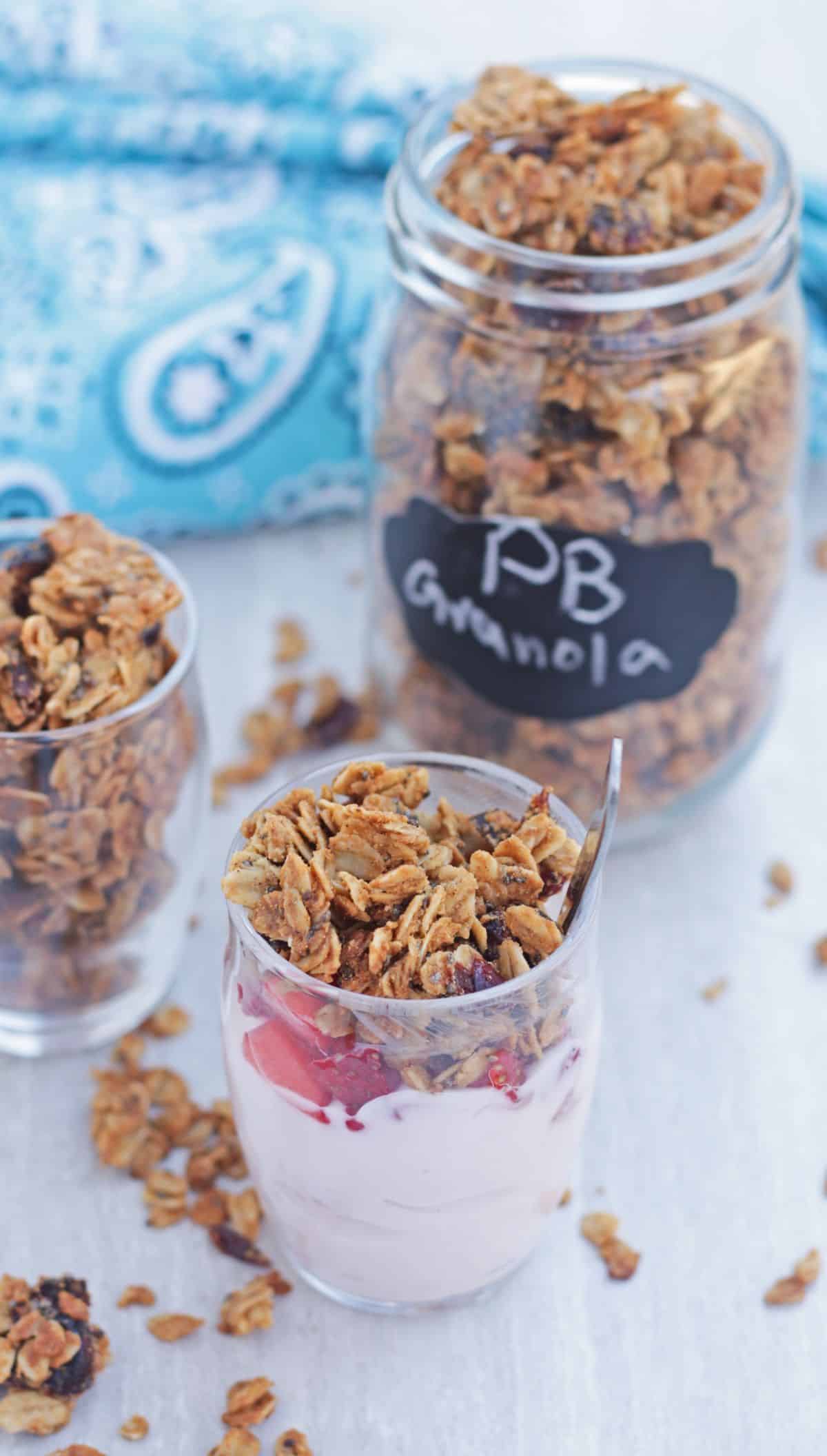 a bowl of yogurt topped with strawberry and granola and a jar of granola in the background