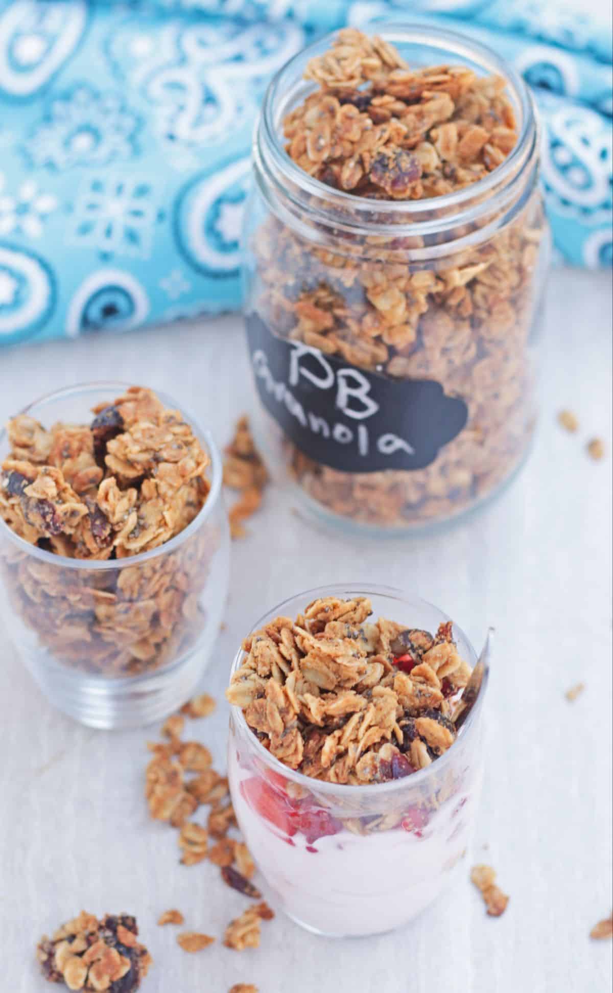 jar of yogurt topped with berries and granola and more granola in the background