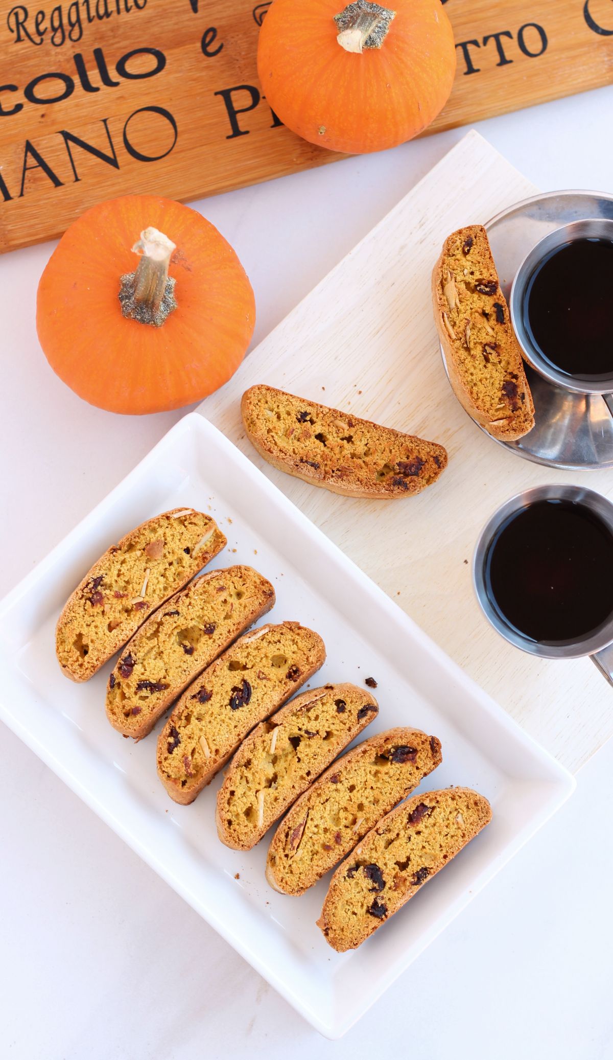 biscotti in a plate with coffee and whole pumpkins on the side