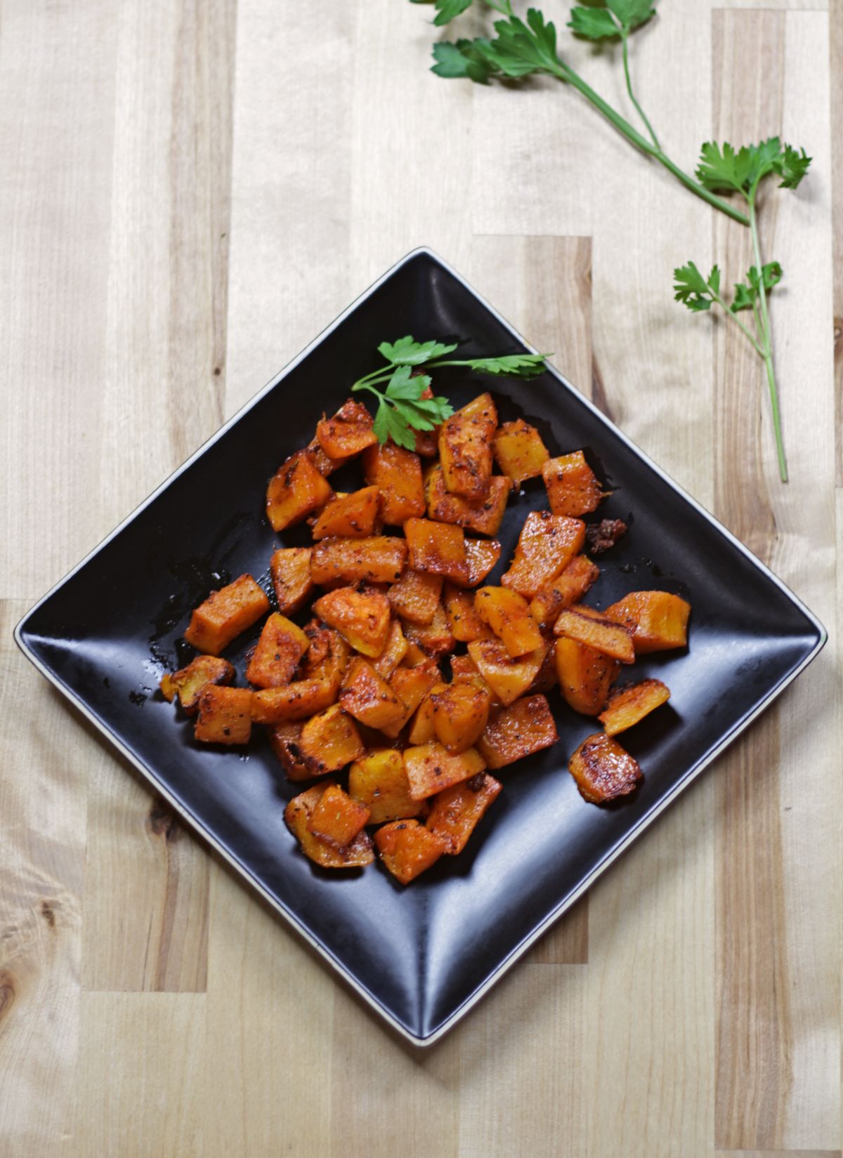 butternut squash in a black plate with fresh herb on the side