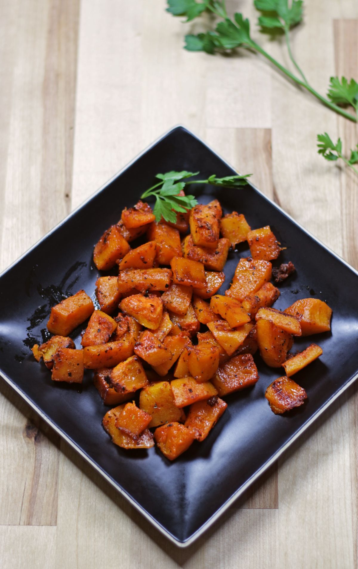 roasted butternut squash in a black plate with fresh herb
