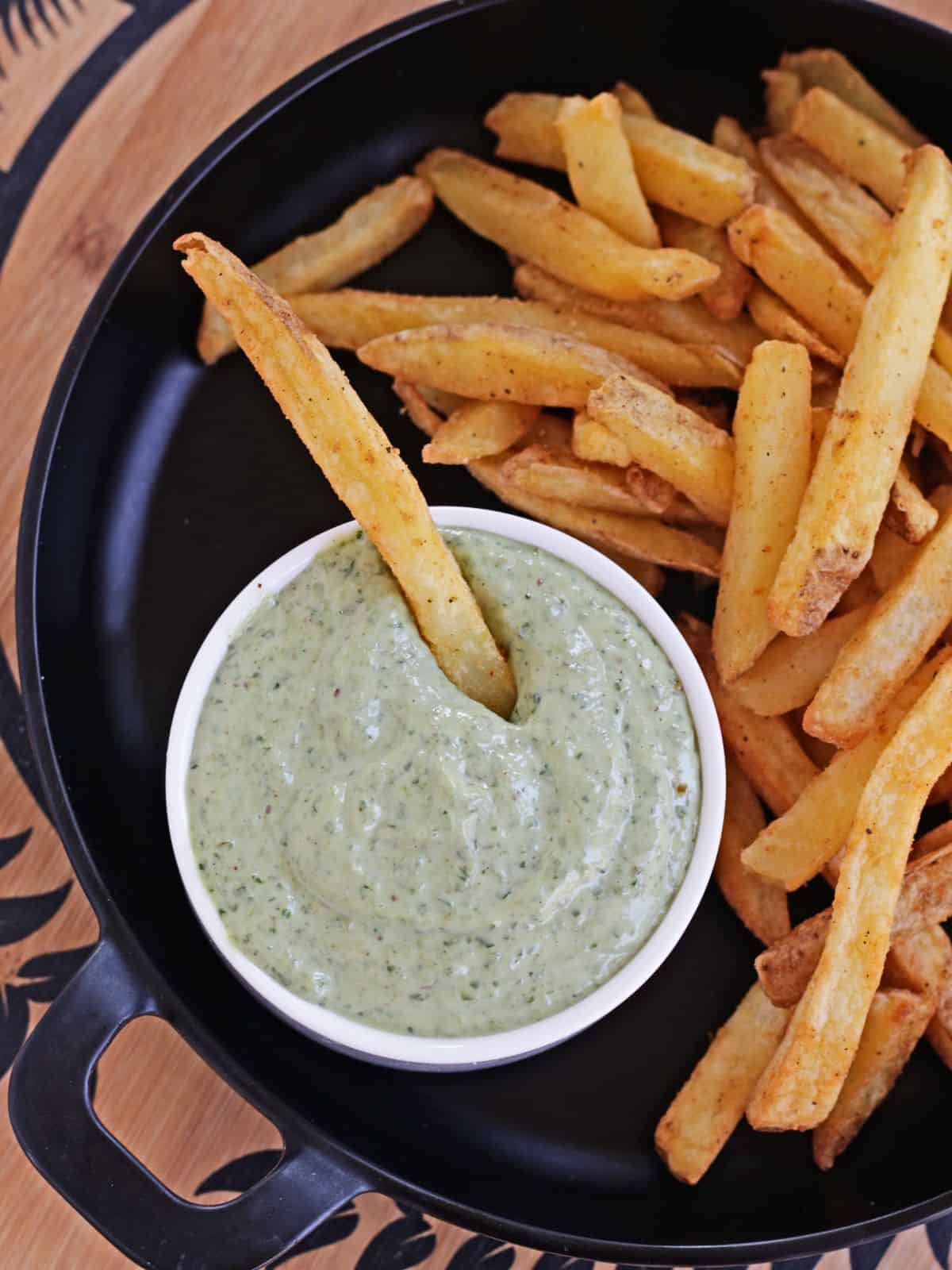 Pesto mayo in a white bowl with potato french fries.