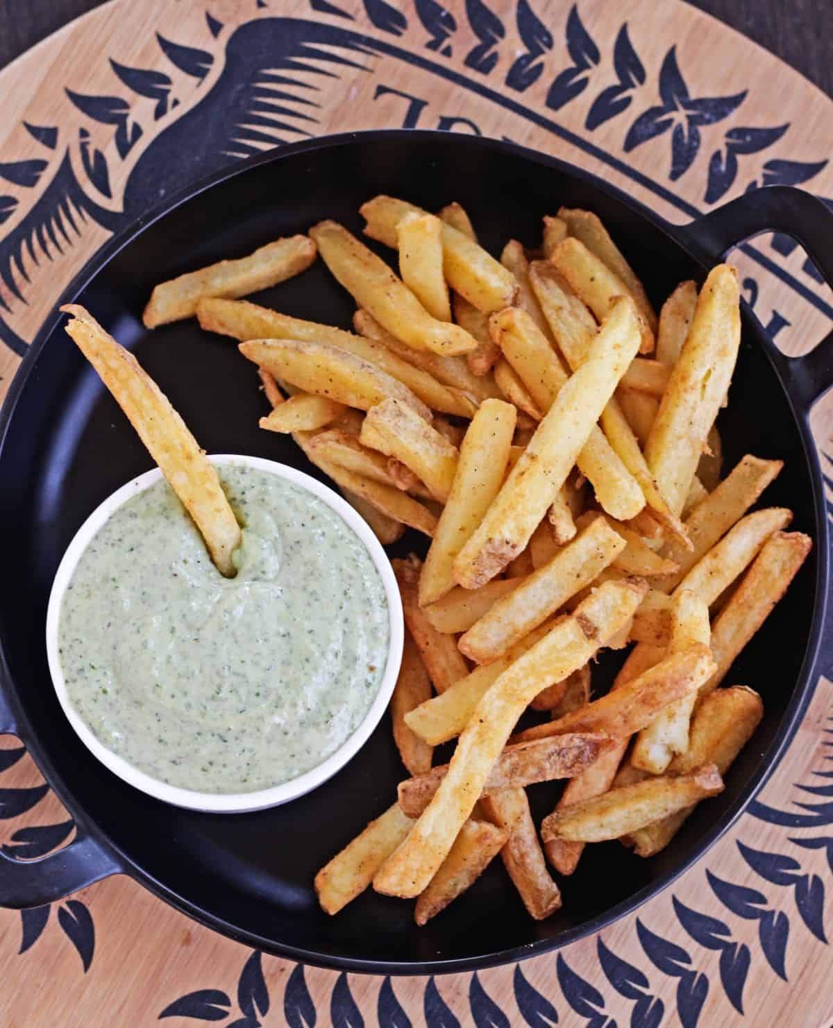 Basil pesto mayo with fries in a black plate