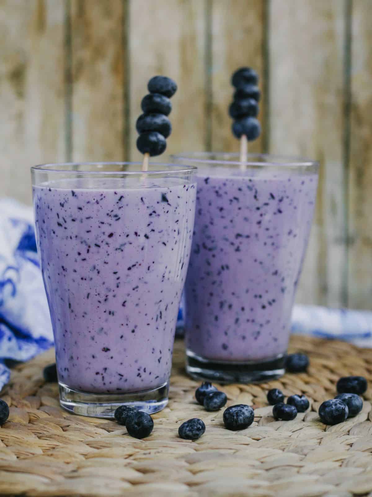 Blueberry lassi in two glasses with blueberry garnish