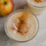 Apple smoothie with straw and cinnamon sprinkled on top.