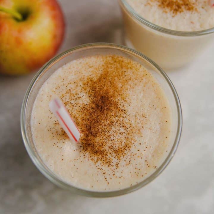 Apple smoothie with straw and cinnamon sprinkled on top.