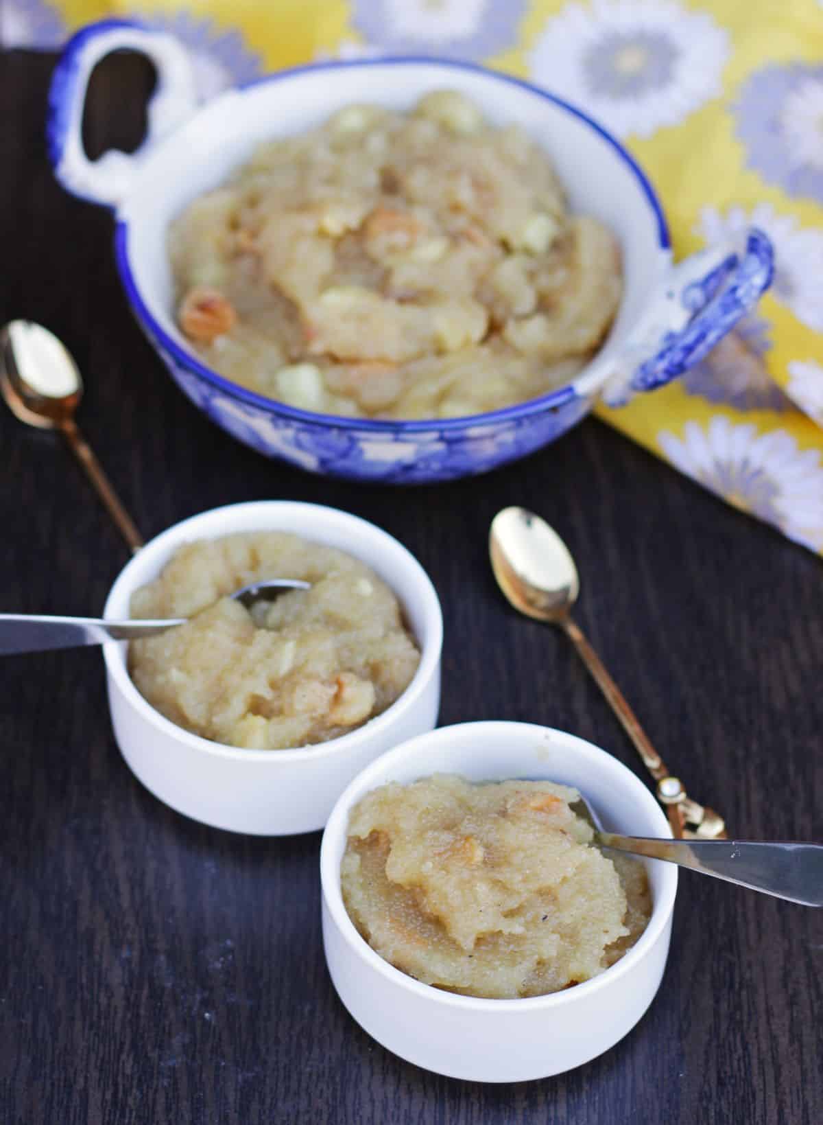 Apple kesari in two bowls and a big bowl with spoons.