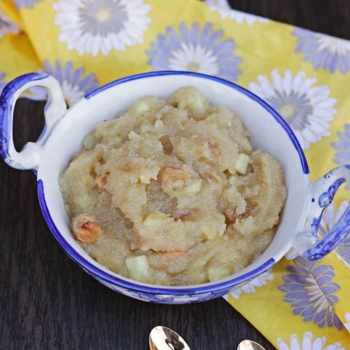 kesari with apple and dry fruits in a white ceramic bowl.