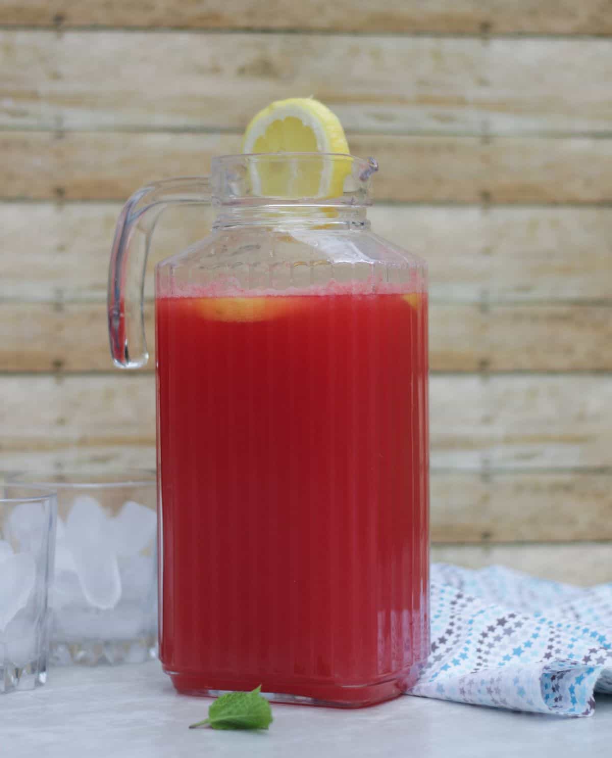 A pitcher of watermelon lemonade with lemon slice garnish.