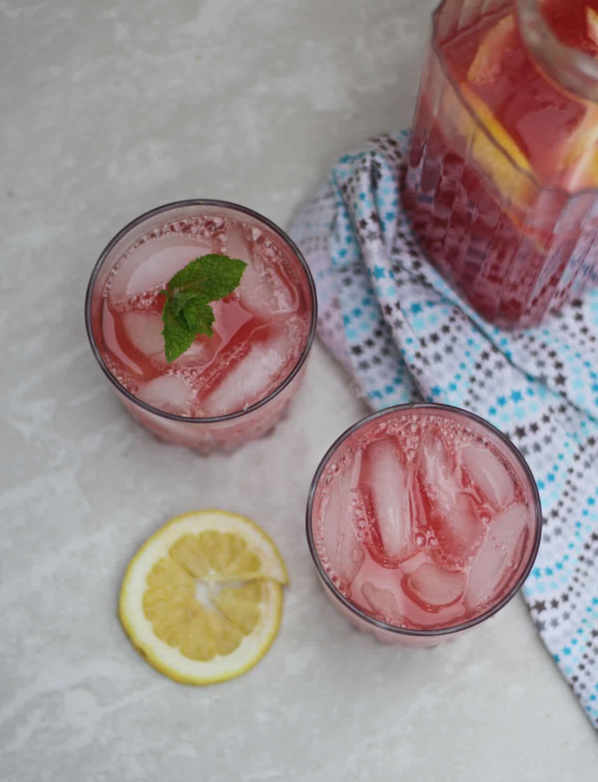 Top view of two glasses with pink lemonade and ice.