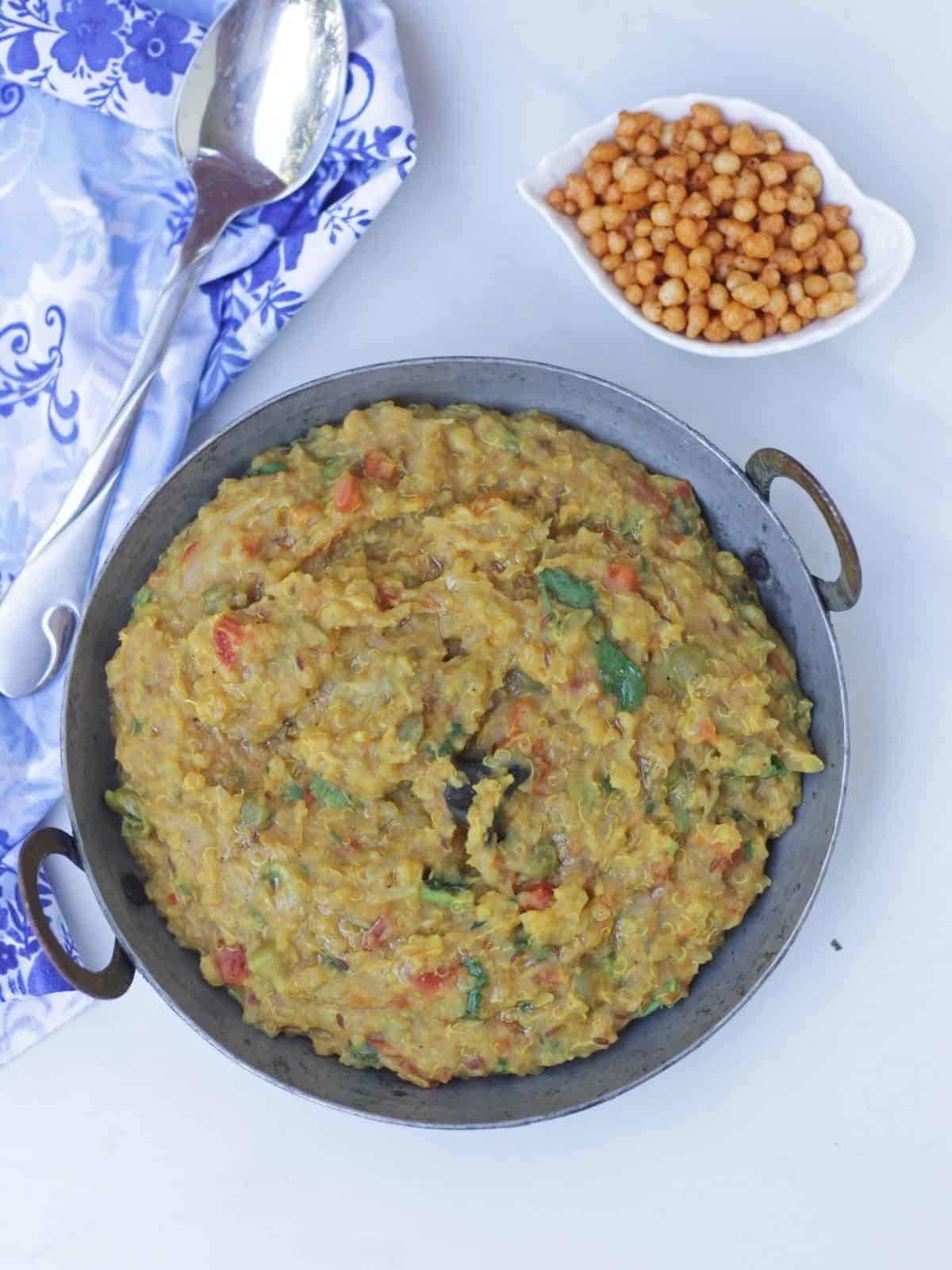 Top view of vegetable and quinoa khichdi with boondi on the side.