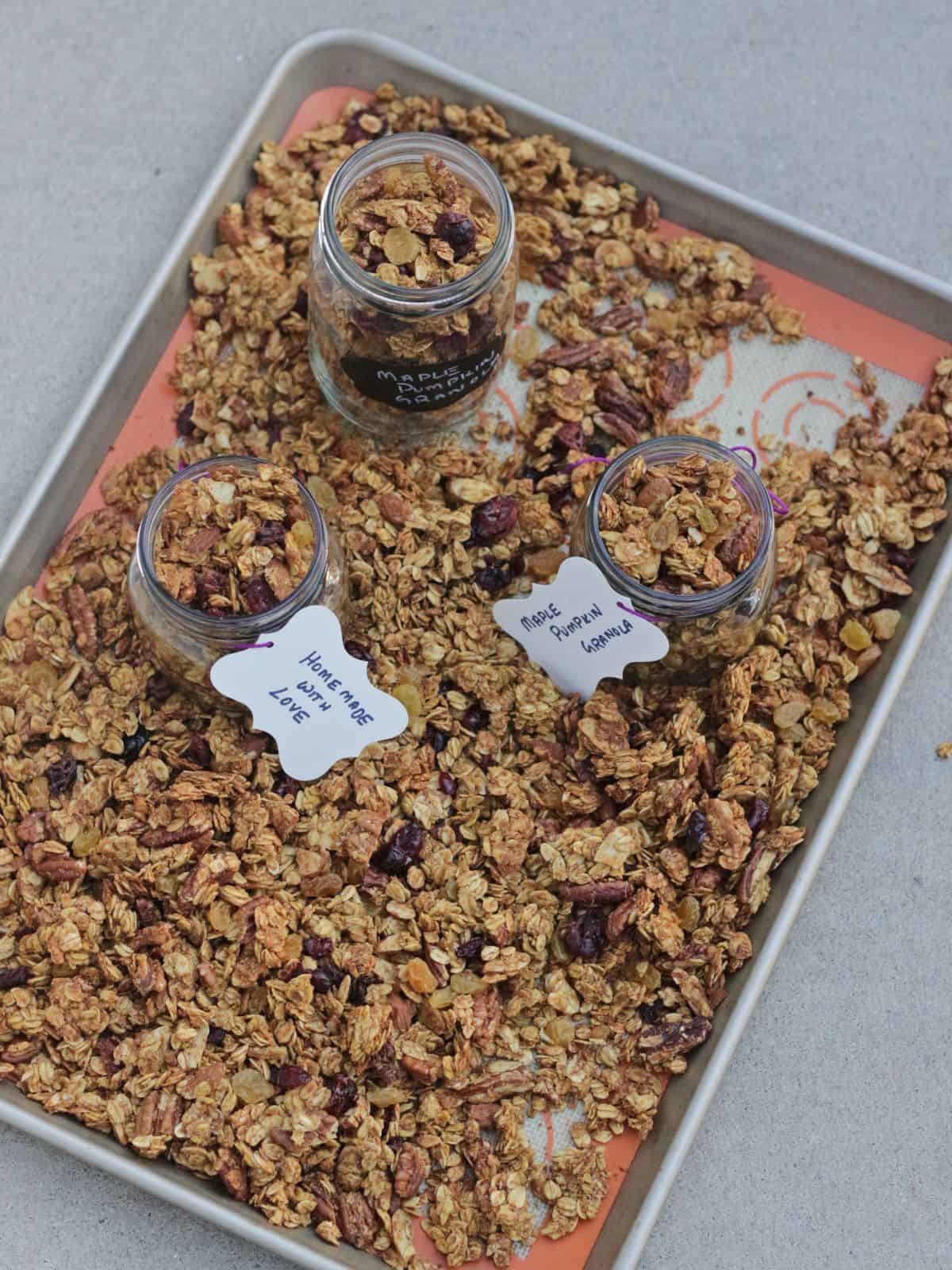 Granola in a tray and in jars on the tray.